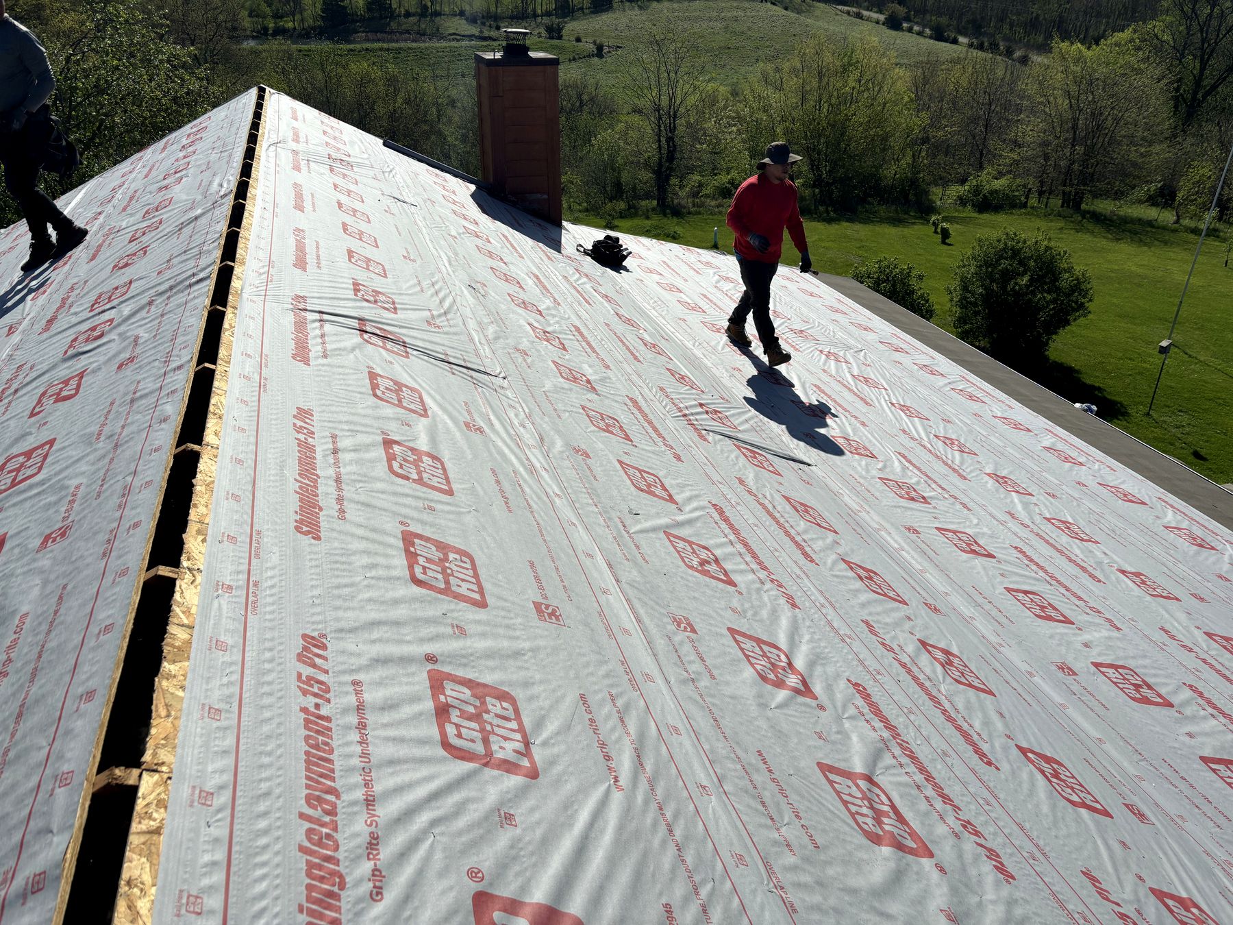 Hackney crew walking synthetic underlayment on a Chariton, Iowa farmhouse roof - tear-off to dried-in in one day