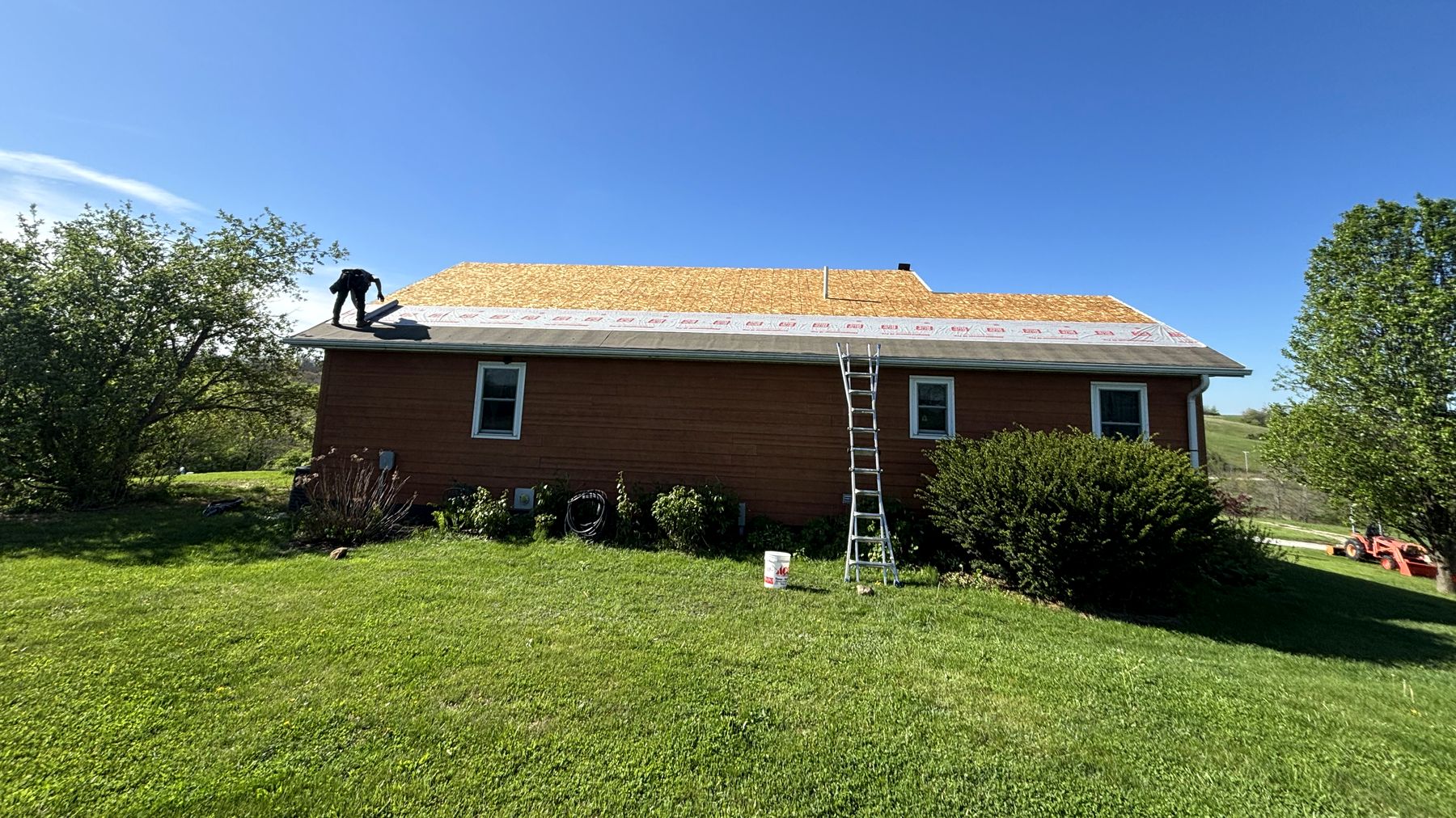 Hackney crew re-decking the roof of a red farmhouse near Chariton, Iowa