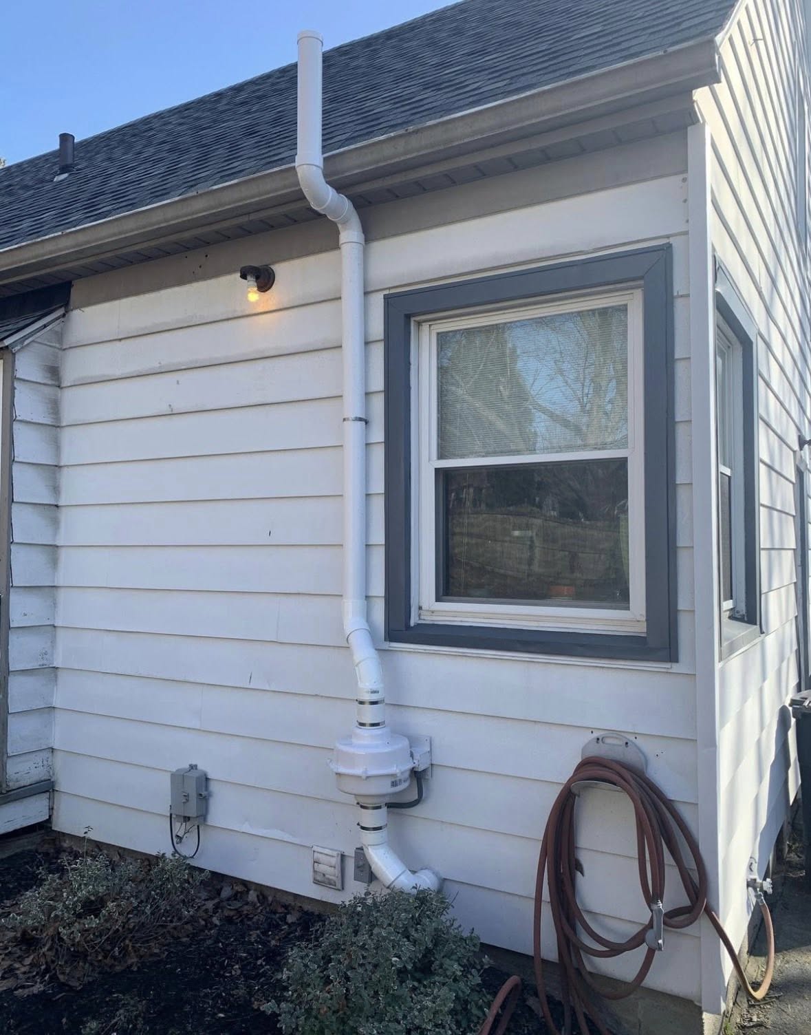 Exterior radon mitigation piping installed on a home